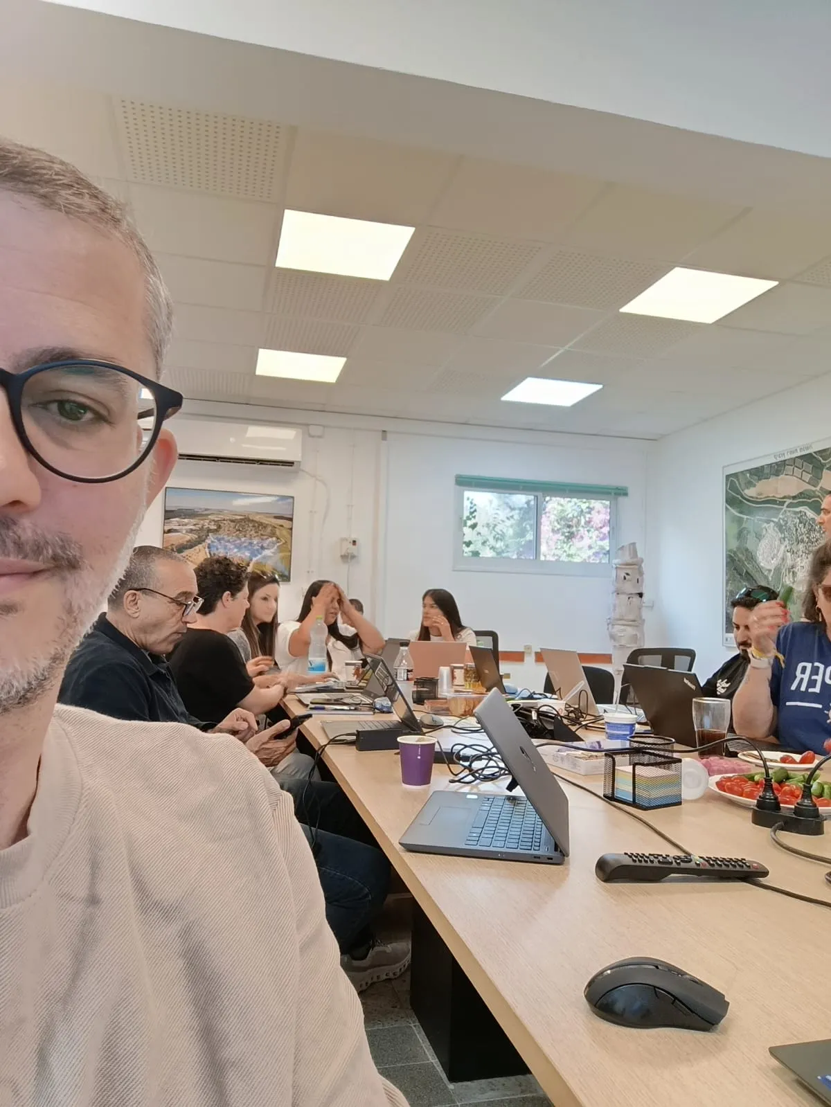 צוות עובד מעשית עם כלי בינה מלאכותית על מחשבים ניידים בסדנה